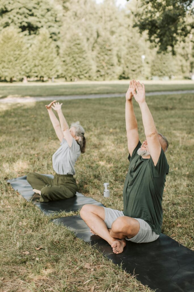 Older adults practicing gentle yoga stretching outdoors in nature, promoting holistic wellness, mindfulness, and active aging