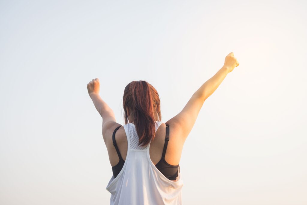 Person raising their arms in confidence, representing positive affirmations, motivation, and personal growth.