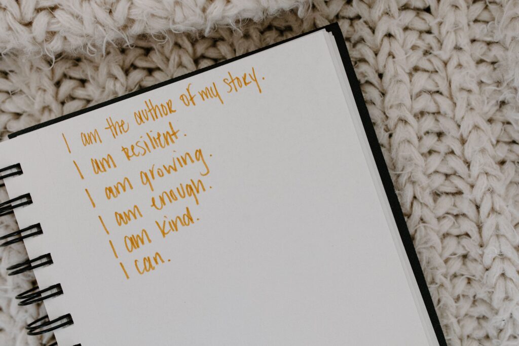 Handwritten positive affirmations in a notebook featuring self-confidence and personal growth statements.